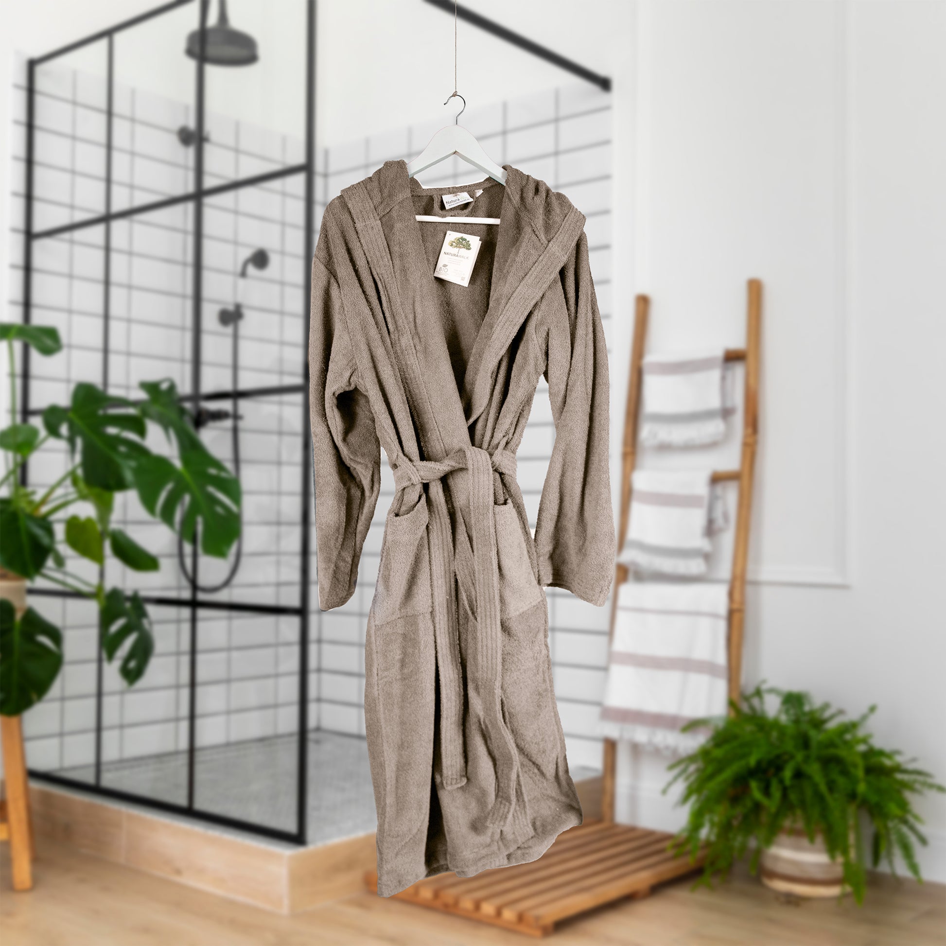 Ein Bademantel mit Kapuze von NATURAWALK aus 100 Prozent Bio-Baumwolle in der Farbe Taupe. Modell Tan.