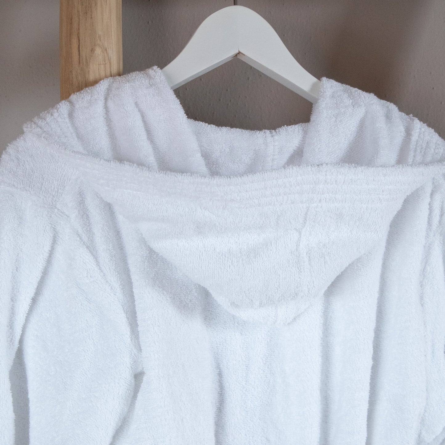 Eine Detailaufnahme der Kapuze vom NATURAWALK Bademantel in der Farbe Weiss. Die Struktur wird hervorgehoben. Modell Weiss.