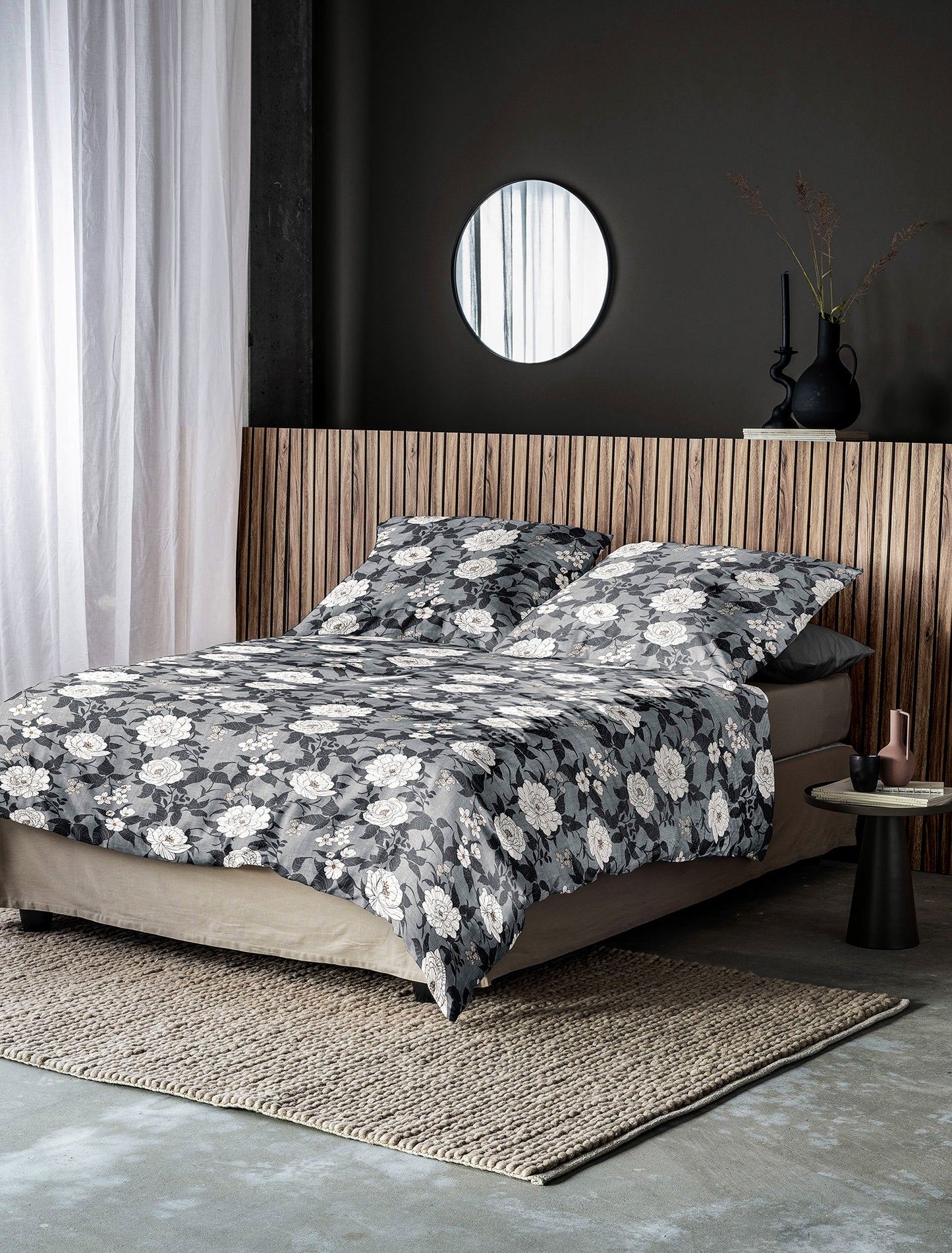 Auf einem Bett liegen mehrere Kopfkissen und eine Bettdecke bezogen mit Edel-Feinbiber Bettwaesche aus 100 Prozent Baumwolle mit Muster aus Blumen in der Farbe Grau. Modell Koala Grau.