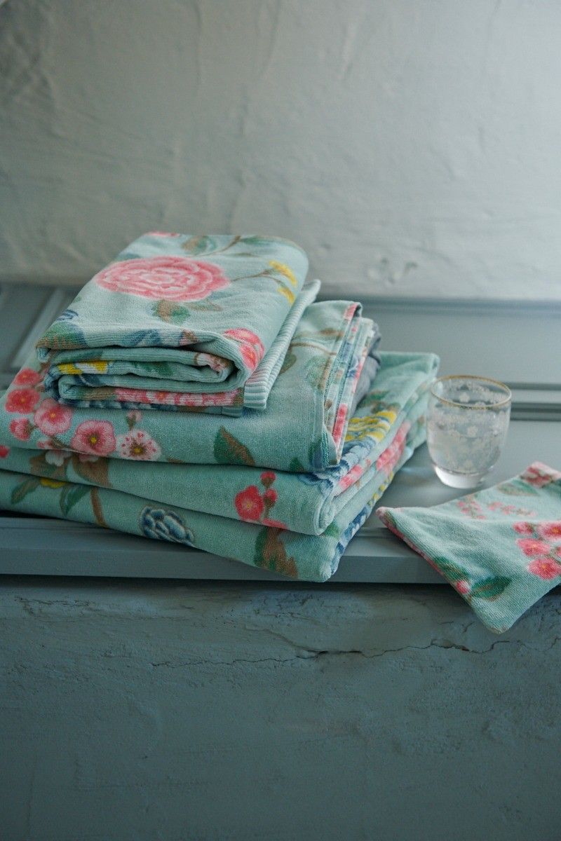 Auf einem Brett liegt ein Stapel aus mehreren Handtuechern von PIP STUDIO die aufeinander liegen mit Muster aus Blumen in der Farbe Blau. Modell Good Evening Blue.