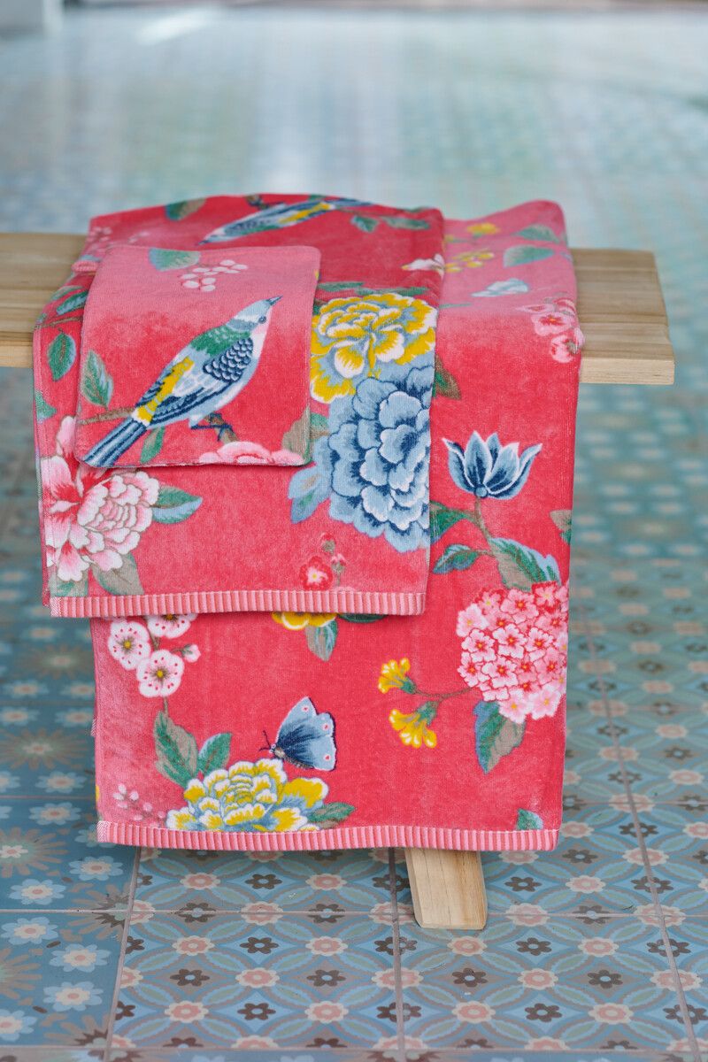 Ein Stapel aus mehreren Handtuechern in verschiedenen Groessen von PIP STUDIO die aufeinander liegen mit Muster aus Blumen und Voegeln in der Farbe Pink. Modell Good Evening Coral.