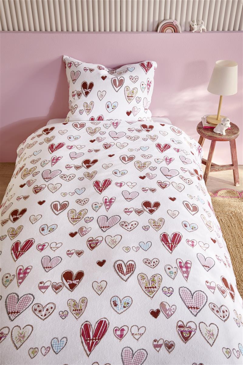 In einem Kinderzimmer steht ein Bett mit einem Kopfkissen und einer Bettdecke bezogen mit kuscheliger beddinghouse Bettwaesche aus 100 Prozent Baumwolle mit Illustrationen von Herzen in der Farbe Weiss. Modell Sweethearts.