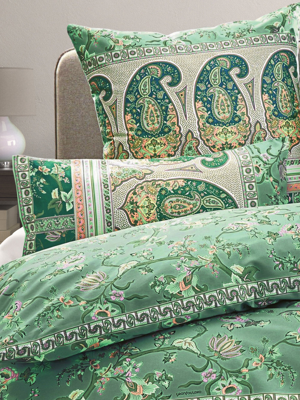 Mehrere Kopfkissen und eine Bettdecke bezogen mit eleganter Mako-Satin Bettwaesche von bassetti mit einem Paisleymuster in der Farbe Gruen. Modell Genova V1