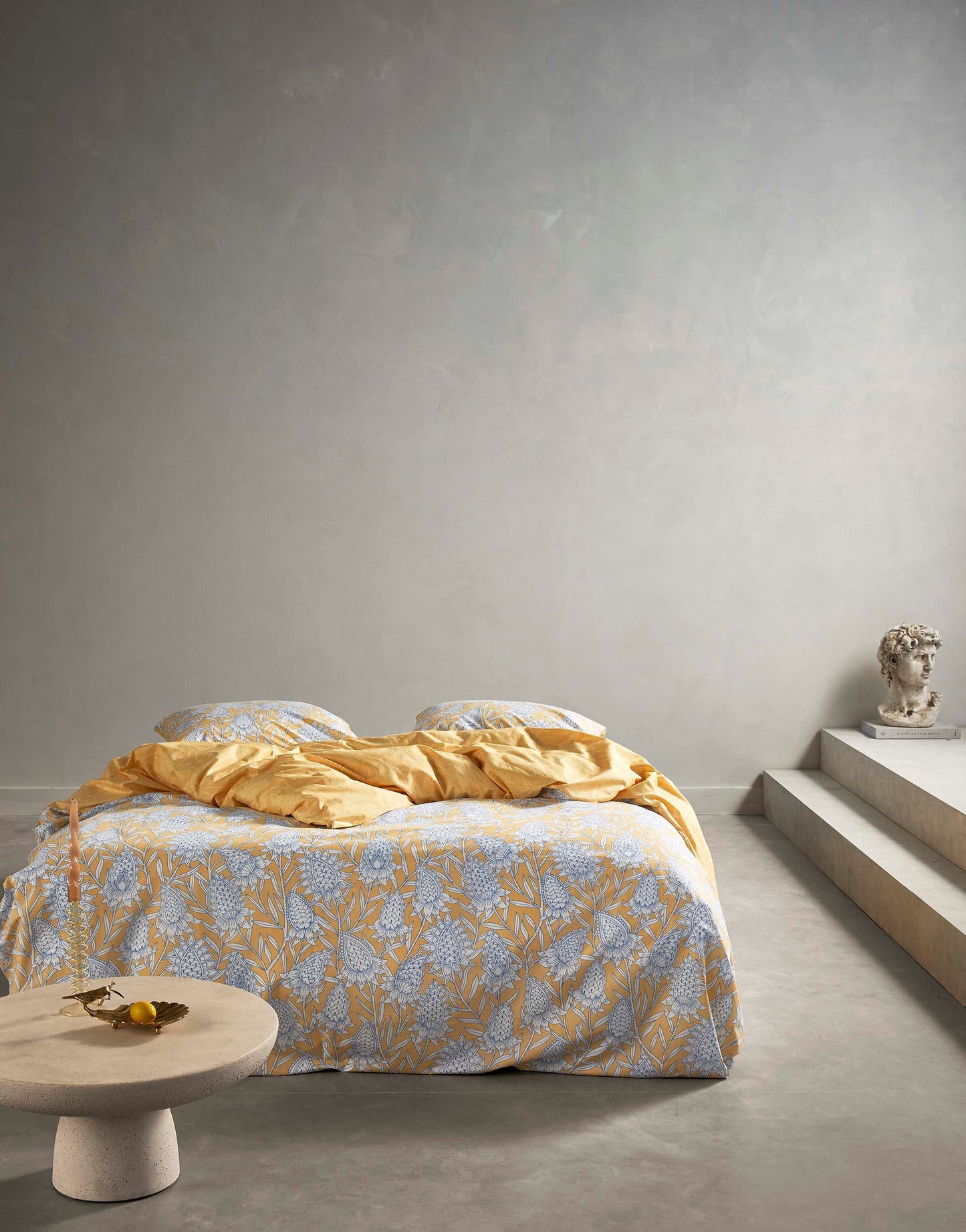 Ein Bettbezug-Set aus einem Kopfkissen und einer Bettdecke bezogen mit Perkal Bettwaesche aus 100 Prozent Baumwolle mit Muster aus Blumen in der Farbe Gelb. Modell Fela Sahara Sun.