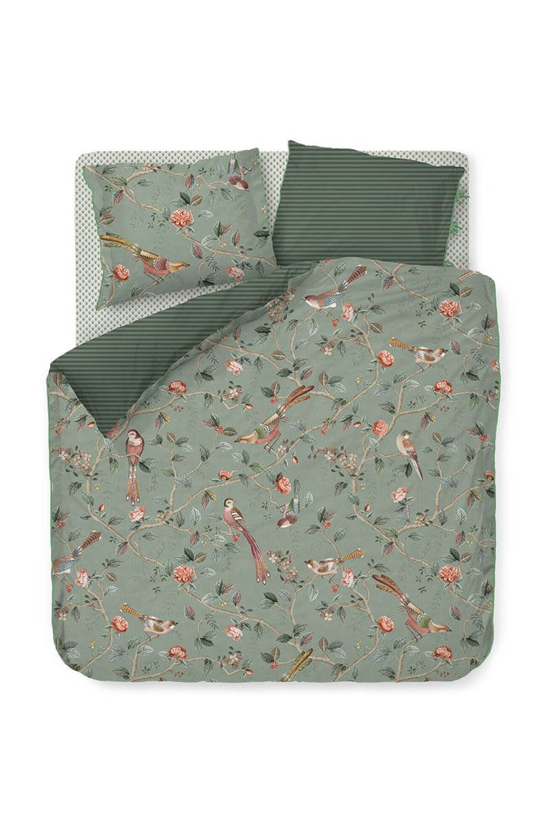 Zwei Kopfkissen und eine Bettdecke bezogen mit Perkal-Baumwoll Bettwaesche mit einem Muster aus Pflanzen und Voegeln in der Farbe Gruen. Modell Good Nightingale Light Green.