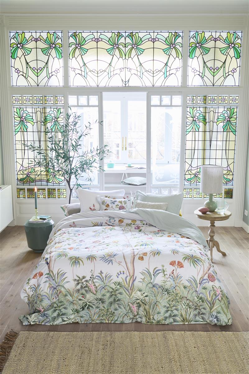 Auf einem Bett liegen mehrere Kopfkissen und eine Bettdecke bezogen mit Perkal-Baumwoll Bettwaesche aus 100 Prozent Baumwolle mit Muster aus Pflanzen und Voegeln in der Farbe Weiss. Modell Il Paradiso Weiss.