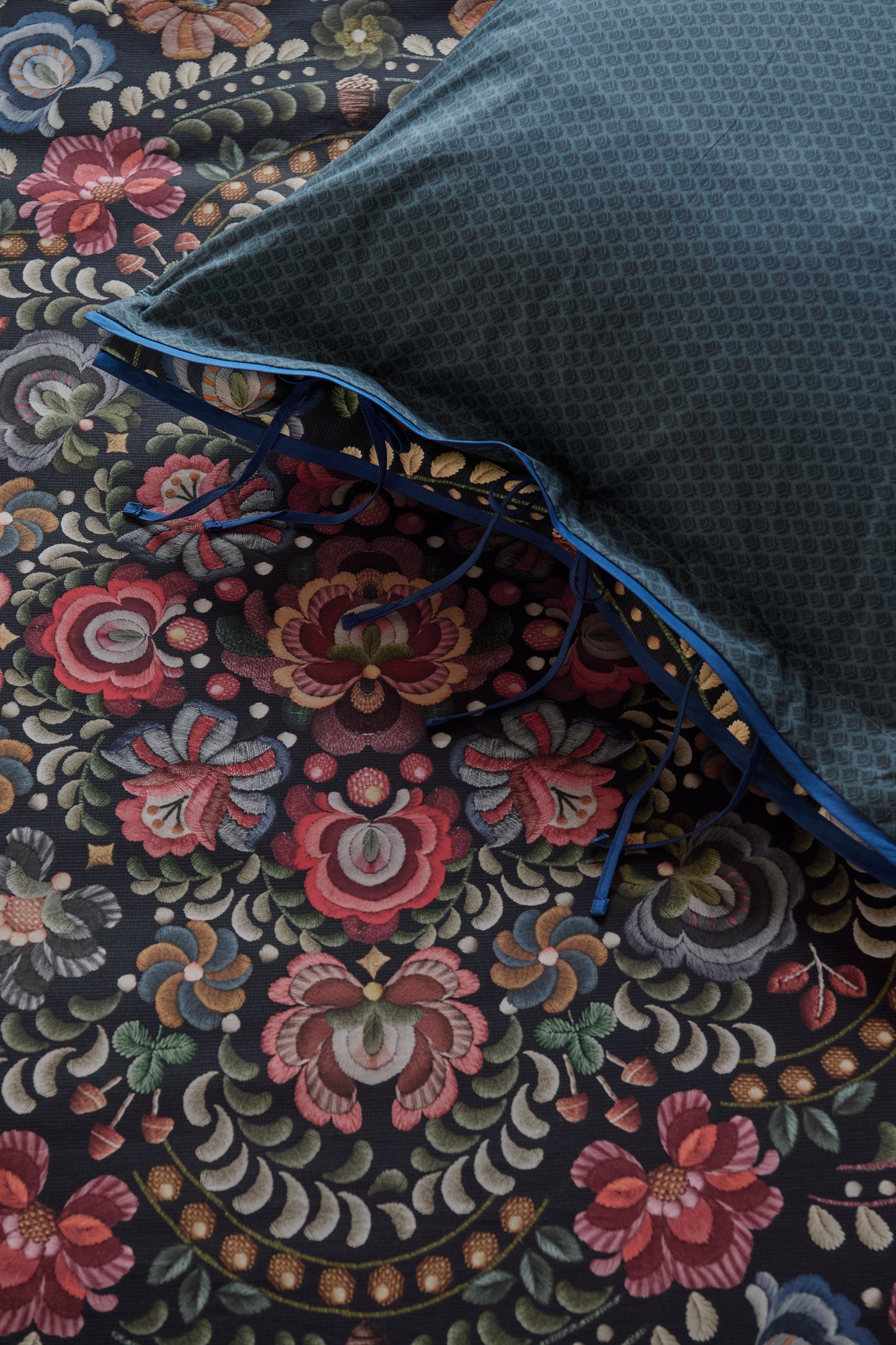 Detaildarstellung der Blumen auf Kopfkissen und Bettdecke der Perkal-Baumwoll Bettwaesche Modell Il Ricamo Dark Blue.