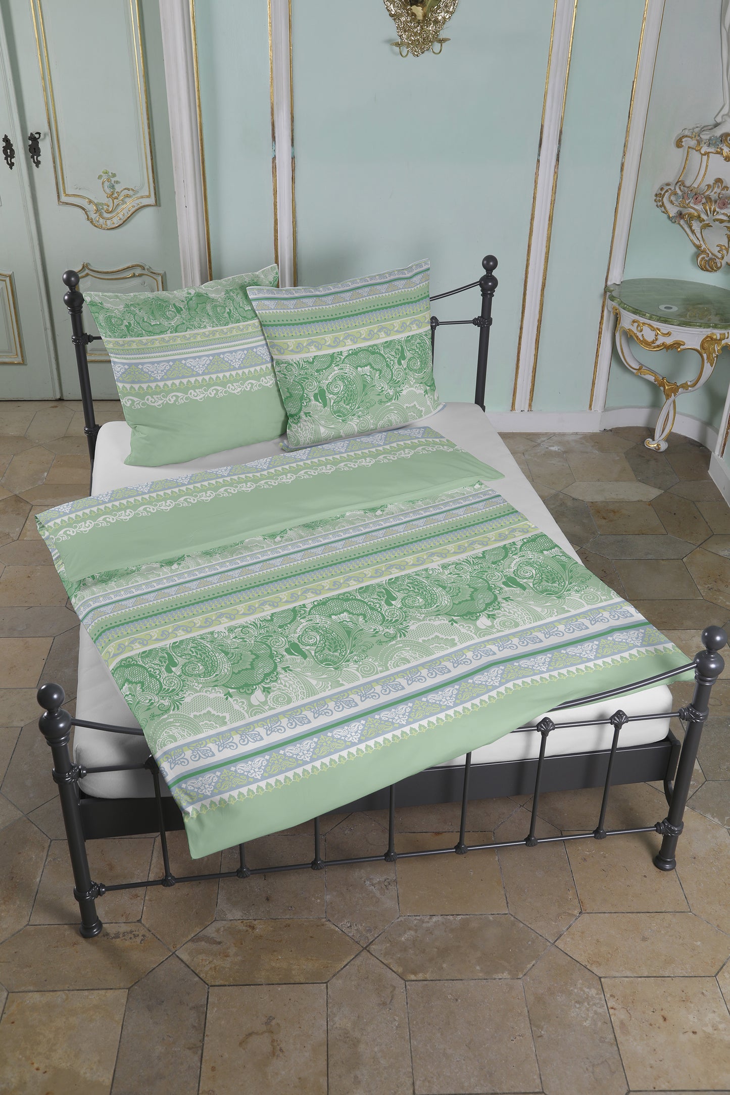 Mehrere Kopfkissen und eine Bettdecke bezogen mit seidig-weicher Satin Bettwaesche von Casatex mit einem Muster in der Farbe Gruen. Modell Kuala Lumpur Lindgruen.