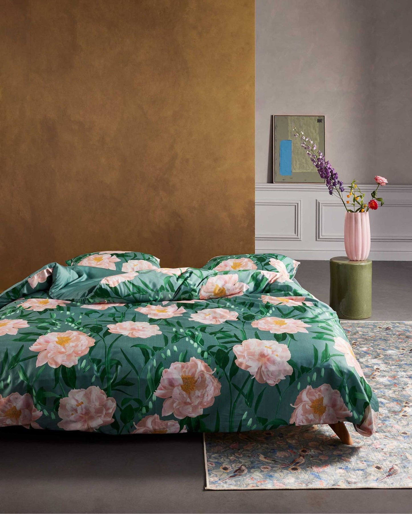 Ein Bettbezug-Set aus mehreren Kopfkissen und einer Bettdecke bezogen mit Satin Bettwaesche aus 100 Prozent Baumwolle mit Muster aus Blumen in der Farbe Gruen. Modell Dorothea Soft Teal.