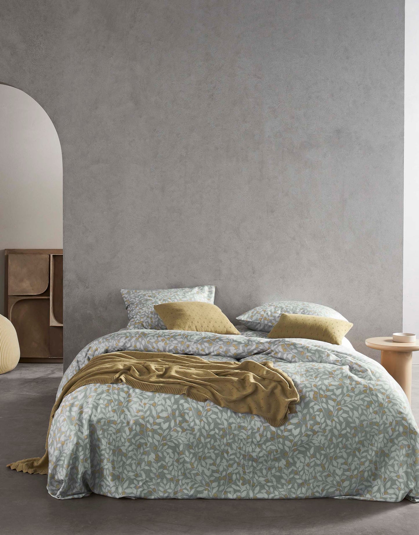Ein Bettbezug-Set aus mehreren Kopfkissen und einer Bettdecke bezogen mit Satin Bettwaesche aus 100 Prozent Baumwolle mit Muster aus Zweigen in der Farbe Grau. Modell Lenthe Cool Gray.