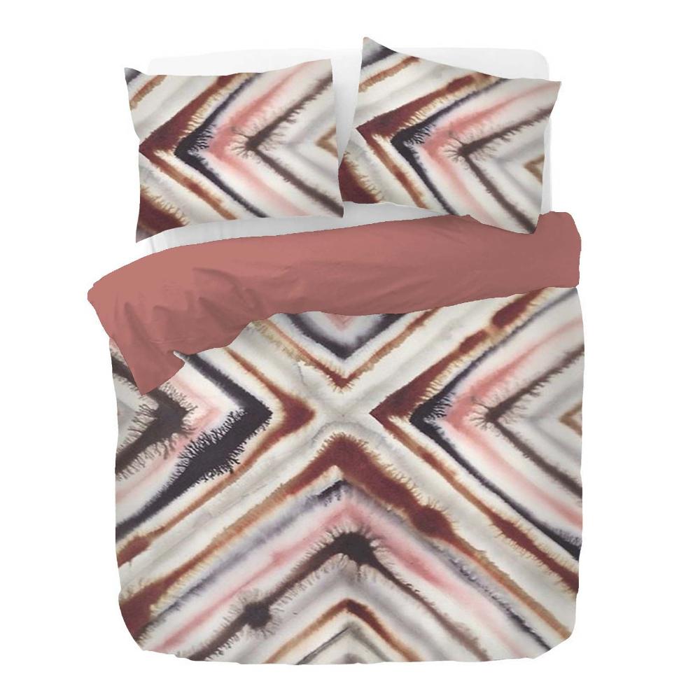 Zwei Kopfkissen und eine Bettdecke bezogen mit Satin Bettwaesche mit einem Muster aus grafischen Formen in der Farbe Rosegold. Modell Sidqi Russet.