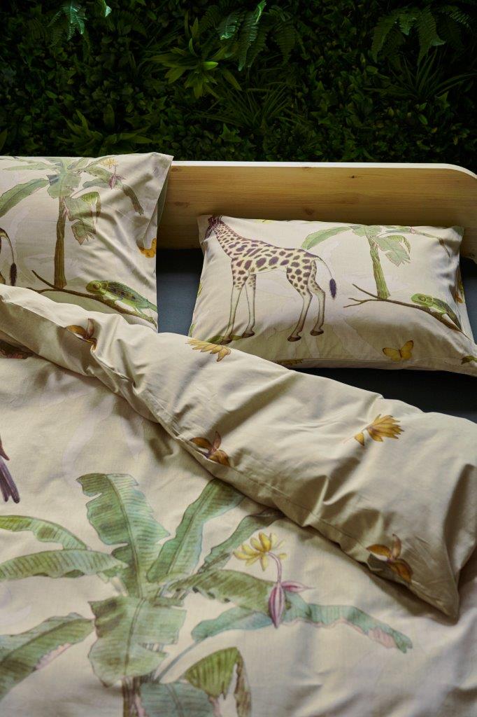 In einem Kinderzimmer steht ein Bett mit einem Kopfkissen und einer Bettdecke bezogen mit kuscheliger Covers & Co Bettwaesche aus 100 Prozent Baumwolle mit Illustrationen vom Dschungel in der Farbe Beige. Modell Banana.