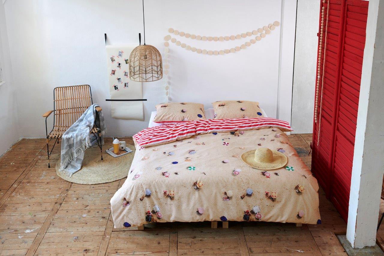 In einem Kinderzimmer steht ein Kinderbett mit einem Kopfkissen und einer Bettdecke bezogen mit kuscheliger Covers & Co Bettwaesche aus 100 Prozent Baumwolle mit Illustrationen vom Strand in der Farbe Beige. Modell Cabana.