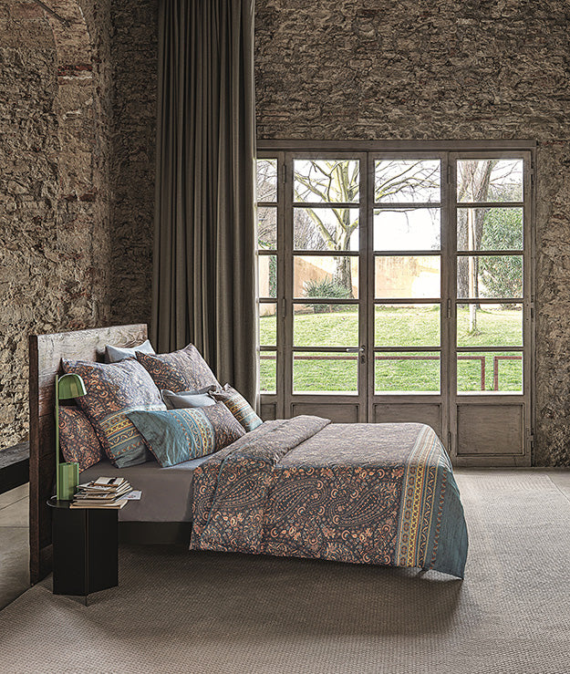 Mehrere Kopfkissen und eine Bettdecke bezogen mit eleganter Mako-Satin Bettwaesche von bassetti mit einem Paisleymuster in der Farbe Blau. Modell Piazza Di Spagna G1.