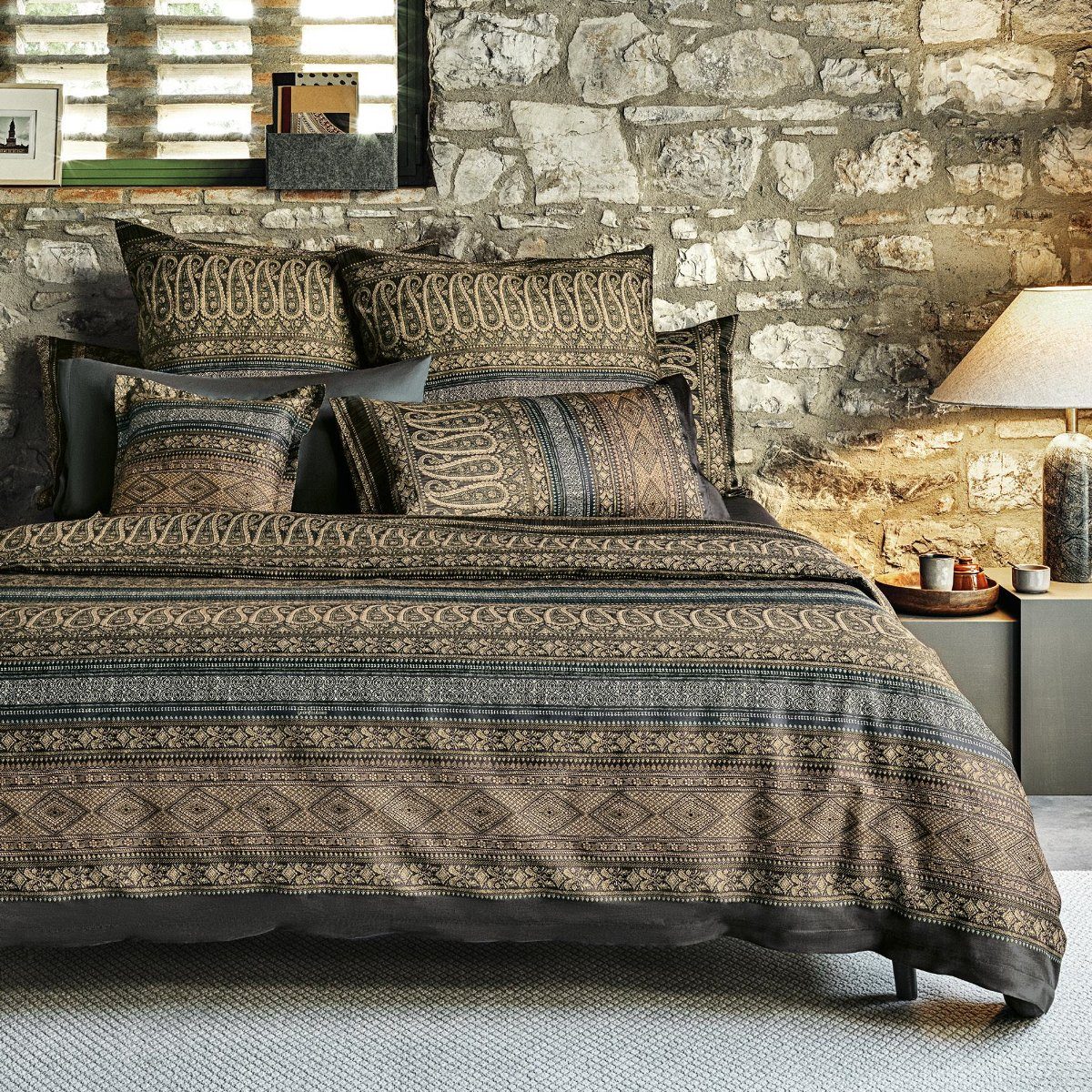 Mehrere Kopfkissen und eine Bettdecke bezogen mit eleganter Mako-Satin Bettwaesche von bassetti mit einem Paisleymuster in der Farbe Braun. Modell Piazza Ducale G1.
