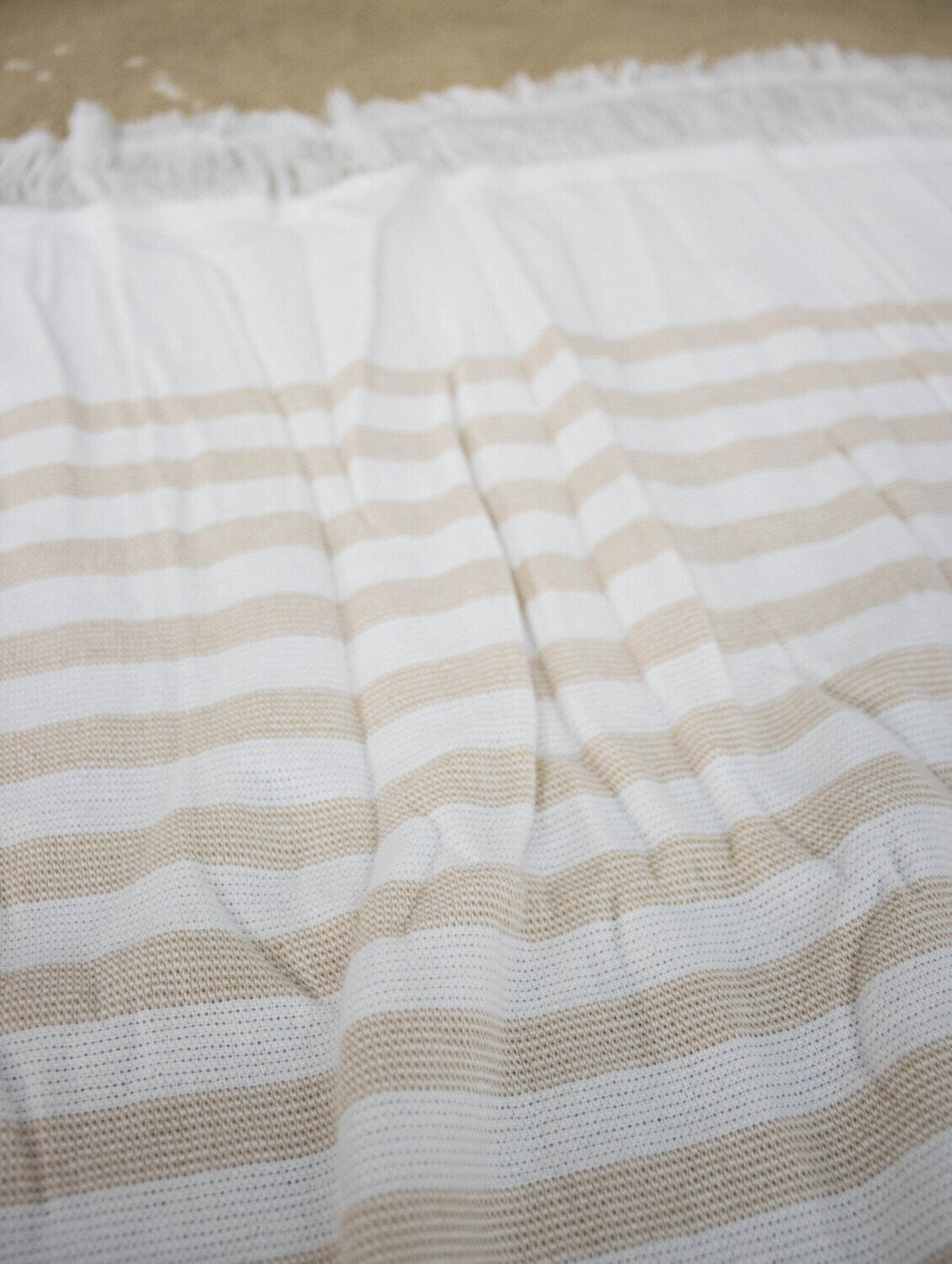 Eine Detailaufnahme des Stoffes vom Standard Line Strandtuch in der Farbe Beige. Die Struktur wird hervorgehoben. Modell Sandnes.