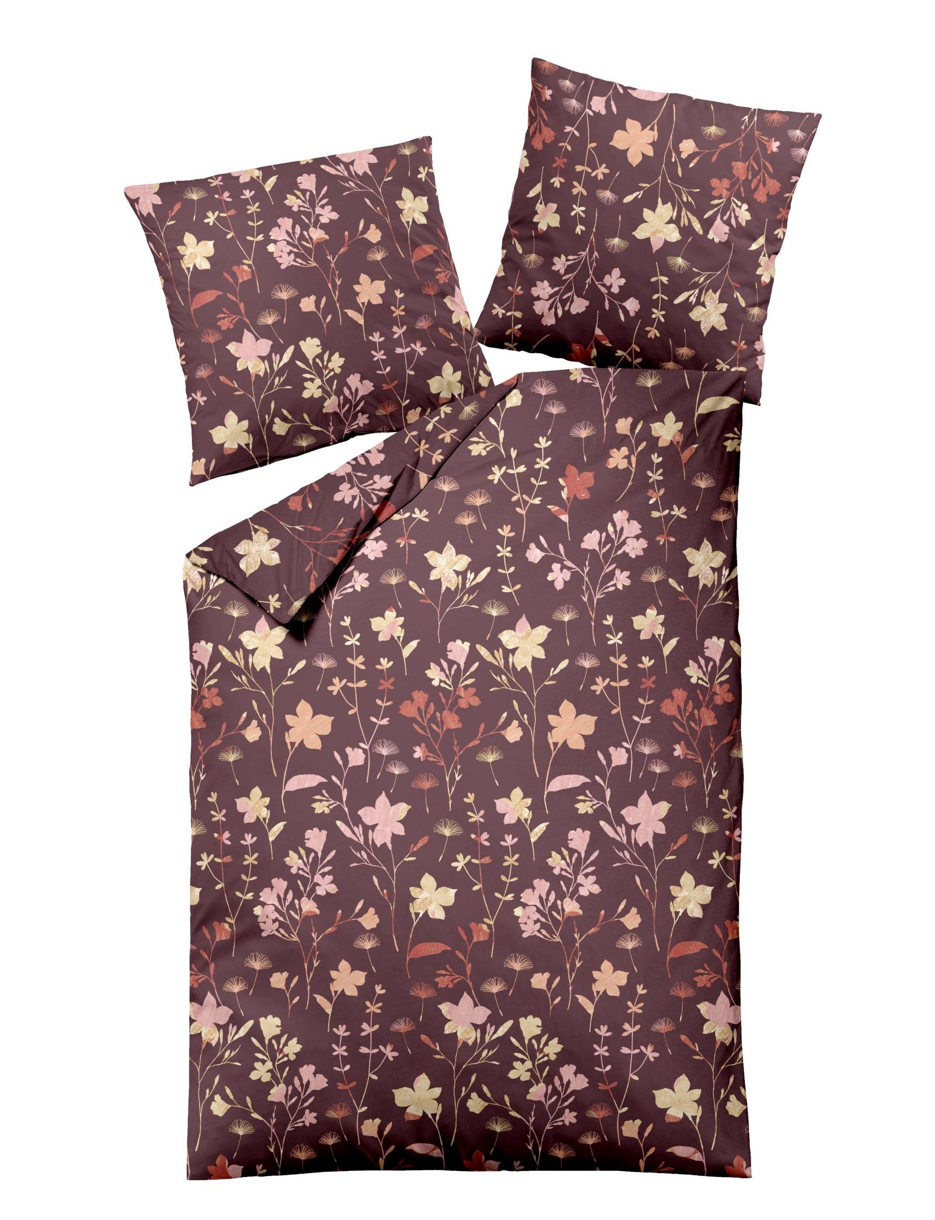 Zwei Kopfkissen und eine Bettdecke bezogen mit Edel-Biber Bettwaesche von Dormisette mit einem Muster aus Blumen in der Farbe Bordeaux. Modell Charm.