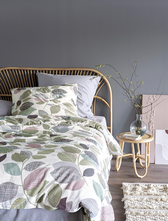 Auf einem Bett liegen mehrere Kopfkissen und eine Bettdecke bezogen mit Edel-Feinbiber Bettwaesche aus 100 Prozent Baumwolle mit Muster aus Blaettern in der Farbe Weiss. Modell Blaetter.