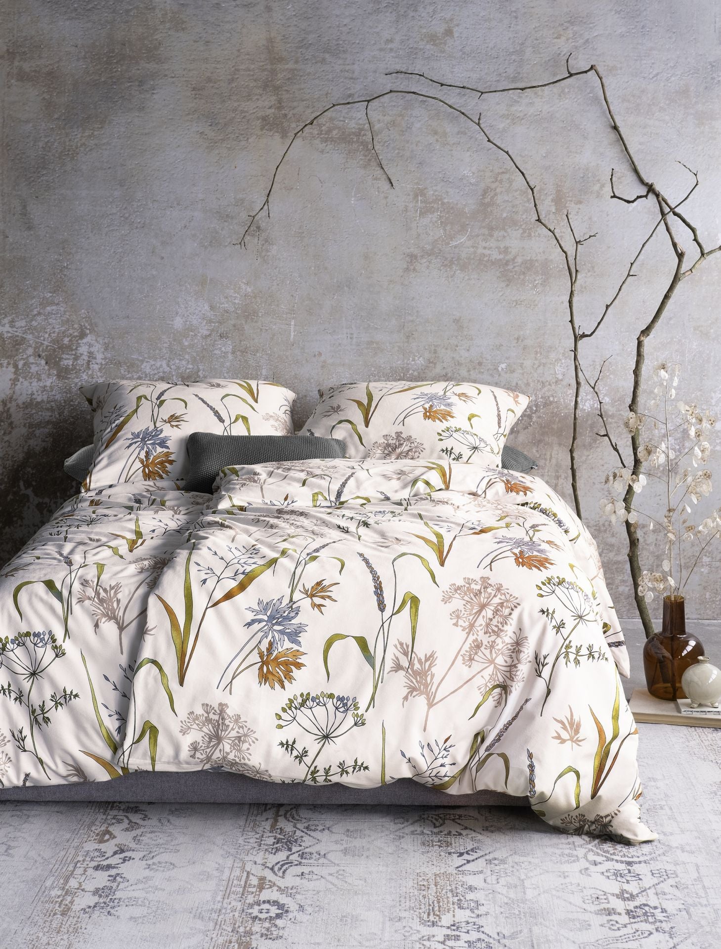 Auf einem Bett liegen mehrere Kopfkissen und eine Bettdecke bezogen mit Edel-Feinbiber Bettwaesche aus 100 Prozent Baumwolle mit Muster aus Graesern in der Farbe Weiss. Modell Graeser.