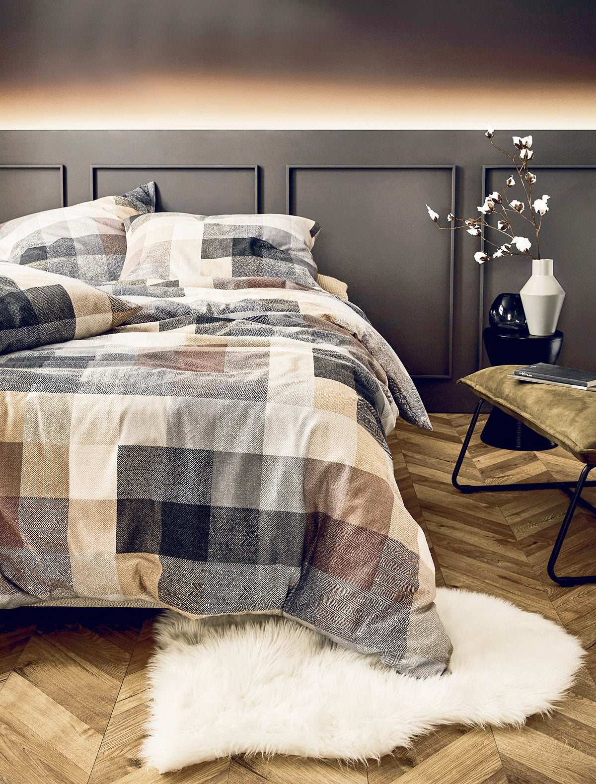 Auf einem Bett liegen mehrere Kopfkissen und eine Bettdecke bezogen mit Edel-Feinbiber Bettwaesche aus 100 Prozent Baumwolle mit Muster aus Quadraten in der Farbe Beige. Modell Karo.