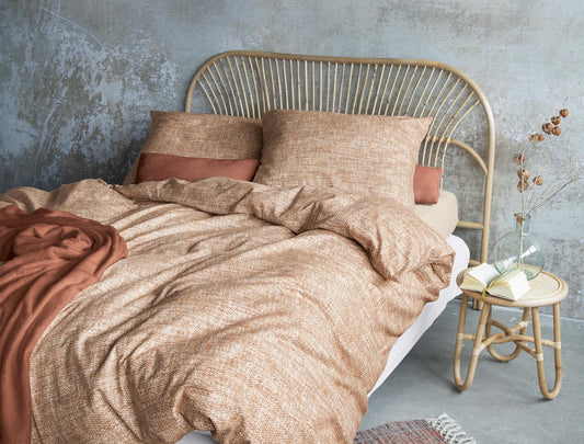 Auf einem Bett liegen mehrere Kopfkissen und eine Bettdecke bezogen mit Edel-Feinbiber Bettwaesche aus 100 Prozent Baumwolle in der Farbe Orange. Modell Koala Ziegel.
