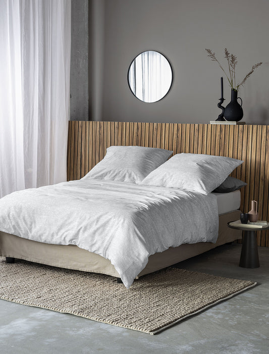 Auf einem Bett liegen mehrere Kopfkissen und eine Bettdecke bezogen mit Edel-Feinbiber Bettwaesche aus 100 Prozent Baumwolle in der Farbe Weiss. Modell Lunaris.