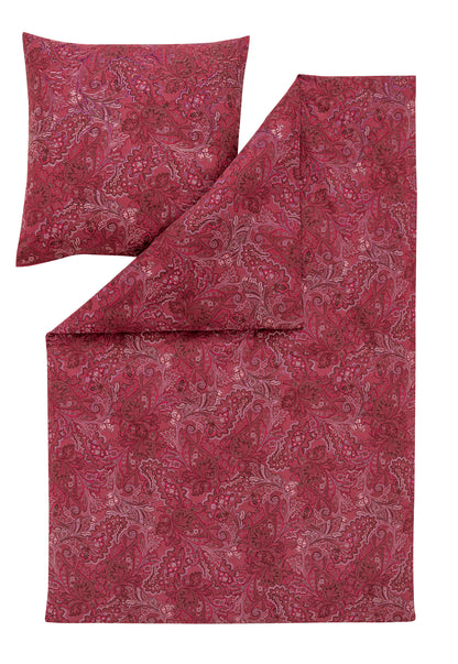 Ein Kopfkissen und eine Bettdecke bezogen mit Edel-Flanell Bettwaesche von Essenza mit einem Muster aus Blueten in der Farbe Rot. Modell Paola Purpur.