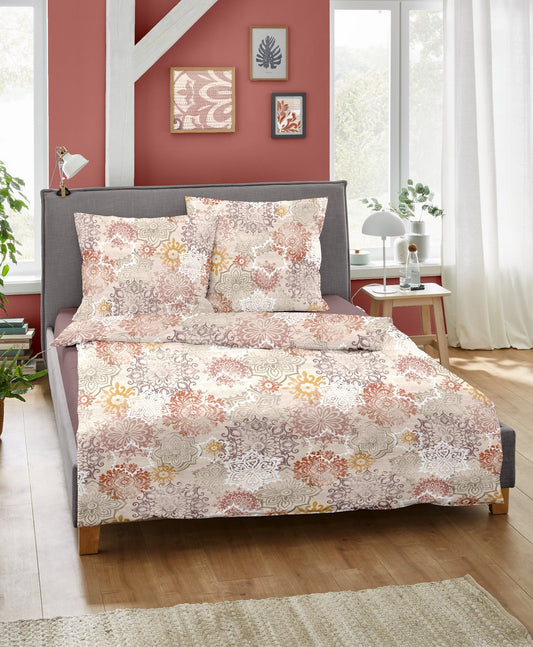 Ein Bettbezug-Set aus einem Kopfkissen und einer Bettdecke bezogen mit Feinbiber Bettwaesche aus 100 Prozent Baumwolle mit Muster aus Ornamenten in der Farbe Beige. Modell Mystic Fields.