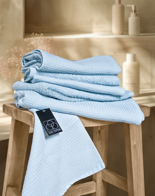 Ein Stapel aus mehreren Handtuechern die aufeinander liegen in der Farbe Blau. Modell Waffelpique Eisblau.