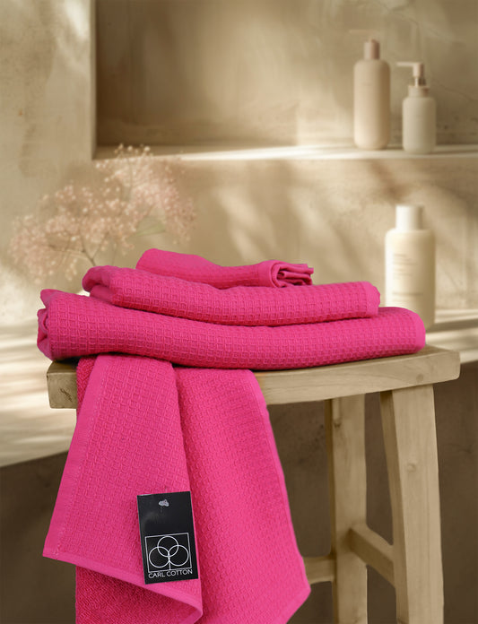 Ein Stapel aus mehreren Handtuechern die aufeinander liegen in der Farbe Pink. Modell Waffelpique Fuchsia. 