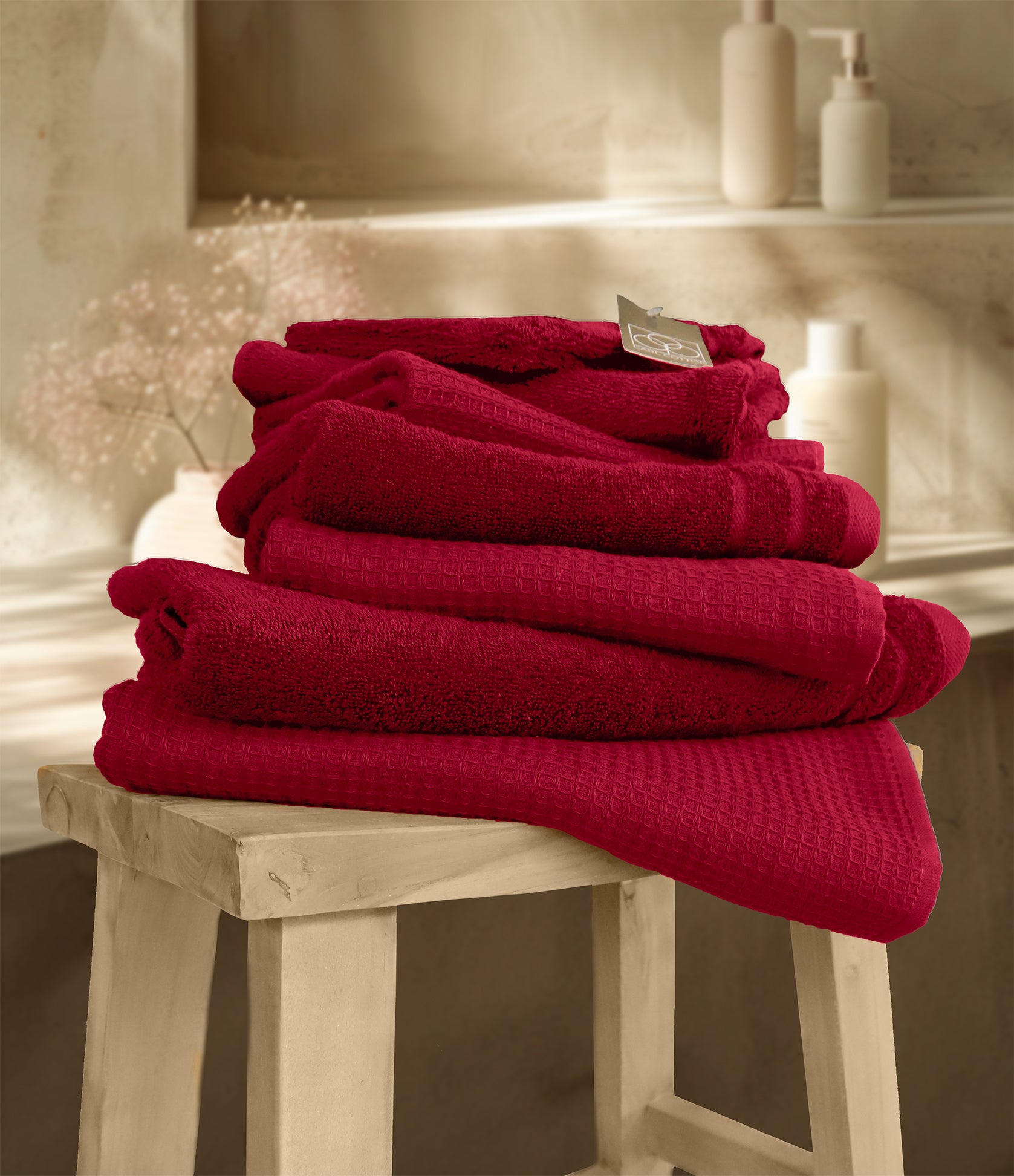 Ein Stapel aus mehreren Handtuechern die aufeinander liegen in der Farbe Bordeaux. Modell Waffelpique Kirsche. 