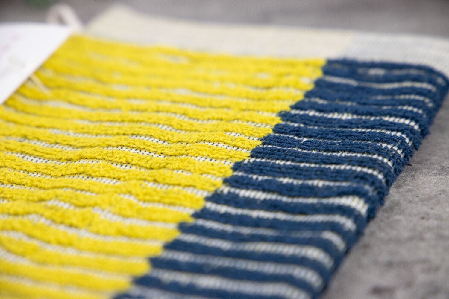 Eine Detailaufnahme eine Waschhandschuhs der Farbe Gelb. Die Struktur wird hervorgehoben. Modell Bloki Mustard.