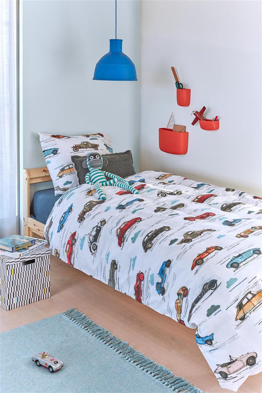 In einem Kinderschlafzimmer steht ein Bett mit einem Kopfkissen und einer Bettdecke bezogen mit kuscheliger beddinghouse Bettwaesche aus 100 Prozent Baumwolle mit Illustrationen von Autos in der Farbe Weiss. Modell Cars. 
