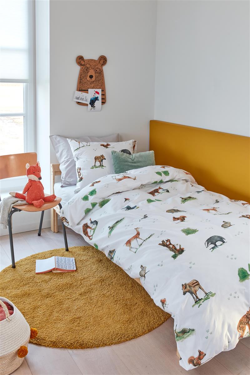 In einem Kinderschlafzimmer steht ein Bett mit einem Kopfkissen und einer Bettdecke bezogen mit kuscheliger beddinghouse Bettwaesche aus 100 Prozent Baumwolle mit Illustrationen von Tieren in der Farbe Weiss. Modell Forest Animals.