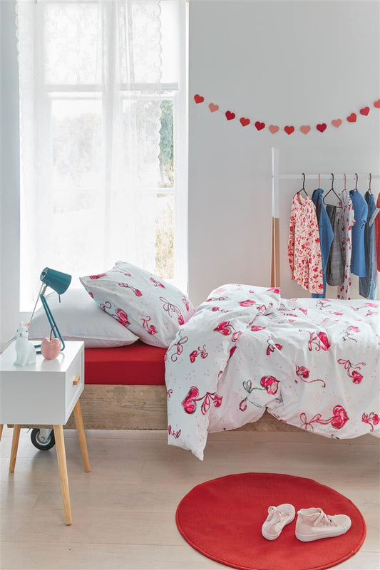 In einem Kinderzimmer steht ein Kinderbett mit einem Kopfkissen und einer Bettdecke bezogen mit kuscheliger beddinghouse Bettwaesche aus 100 Prozent Baumwolle mit Illustrationen von Herzen und Schleifen in der Farbe Weiss. Modell Love.