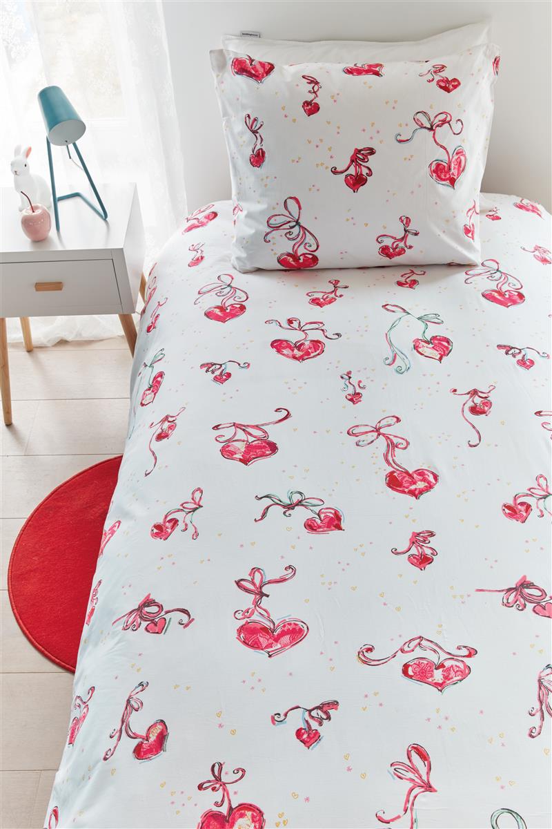In einem Kinderzimmer steht ein Bett mit einem Kopfkissen und einer Bettdecke bezogen mit kuscheliger beddinghouse Bettwaesche aus 100 Prozent Baumwolle mit Illustrationen von Herzen und Schleifen  in der Farbe Weiss. Modell Love.