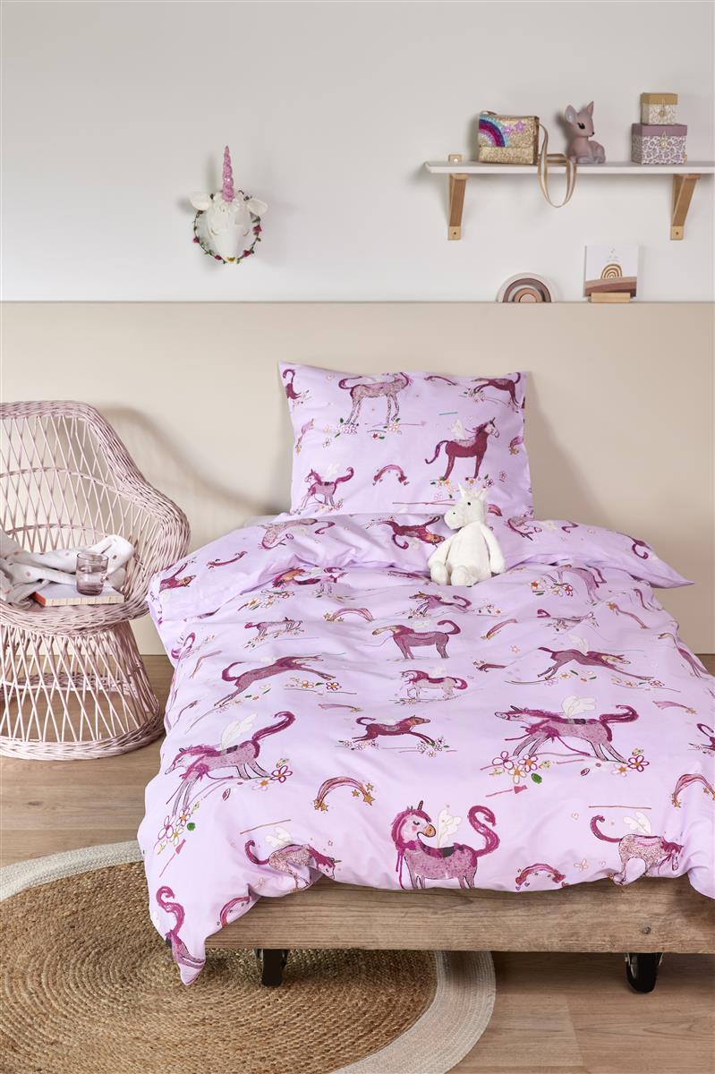 In einem Kinderzimmer steht ein Kinderbett mit einem Kopfkissen und einer Bettdecke bezogen mit kuscheliger beddinghouse Bettwaesche aus 100 Prozent Baumwolle mit Illustrationen von Einhörnern in der Farbe Rosa. Modell Unicorns.