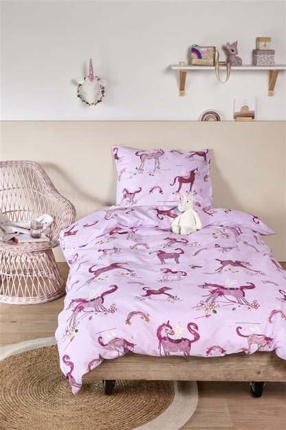 In einem Kinderzimmer steht ein Kinderbett mit einem Kopfkissen und einer Bettdecke bezogen mit kuscheliger beddinghouse Bettwaesche aus 100 Prozent Baumwolle mit Illustrationen von Einhörnern in der Farbe Rosa. Modell Unicorns.