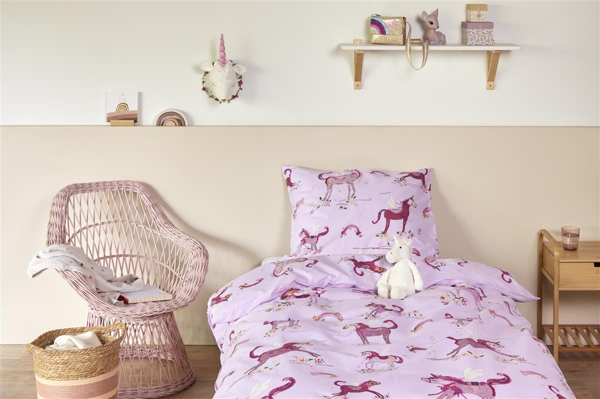 In einem Kinderzimmer steht ein Bett mit einem Kopfkissen und einer Bettdecke bezogen mit kuscheliger beddinghouse Bettwaesche aus 100 Prozent Baumwolle mit Illustrationen von Einhörnern in der Farbe Rosa. Modell Unicorns.