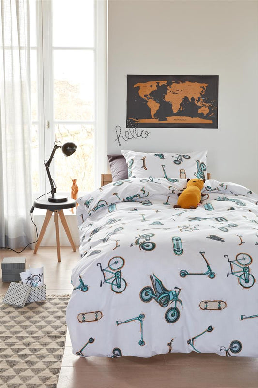 In einem Kinderzimmer steht ein Kinderbett mit einem Kopfkissen und einer Bettdecke bezogen mit kuscheliger beddinghouse Bettwaesche aus 100 Prozent Baumwolle mit Illustrationen von Fortbewegungsmitteln mit Raedern in der Farbe Weiss. Modell Wheels.