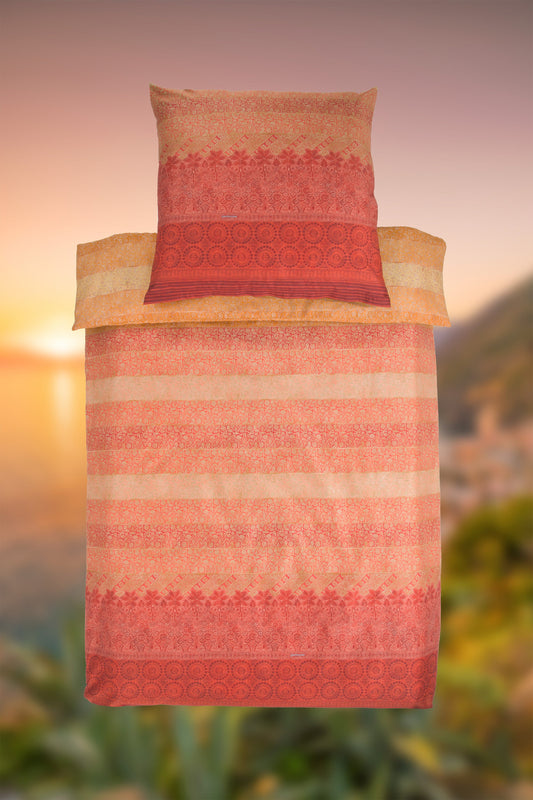 Ein Kopfkissen und eine Bettdecke bezogen mit eleganter Mako-Satin Bettwaesche von bassetti mit einem Paisleymuster in der Farbe Orange. Modell Appiani RB.