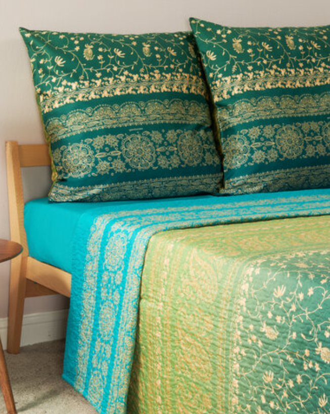 Zwei gruene Kopfkissen und eine mehrfarbige Bettdecke bezogen mit eleganter Mako-Satin Bettwaesche von bassetti mit einem Paisleymuster in der Farbe Gruen. Modell Brenta V1