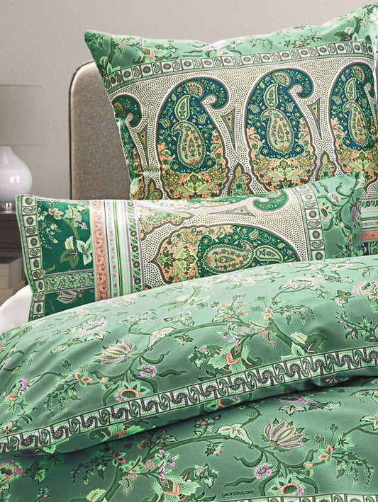 Mehrere Kopfkissen und eine Bettdecke bezogen mit eleganter Mako-Satin Bettwaesche von bassetti mit einem Paisleymuster in der Farbe Gruen. Modell Genova V1
