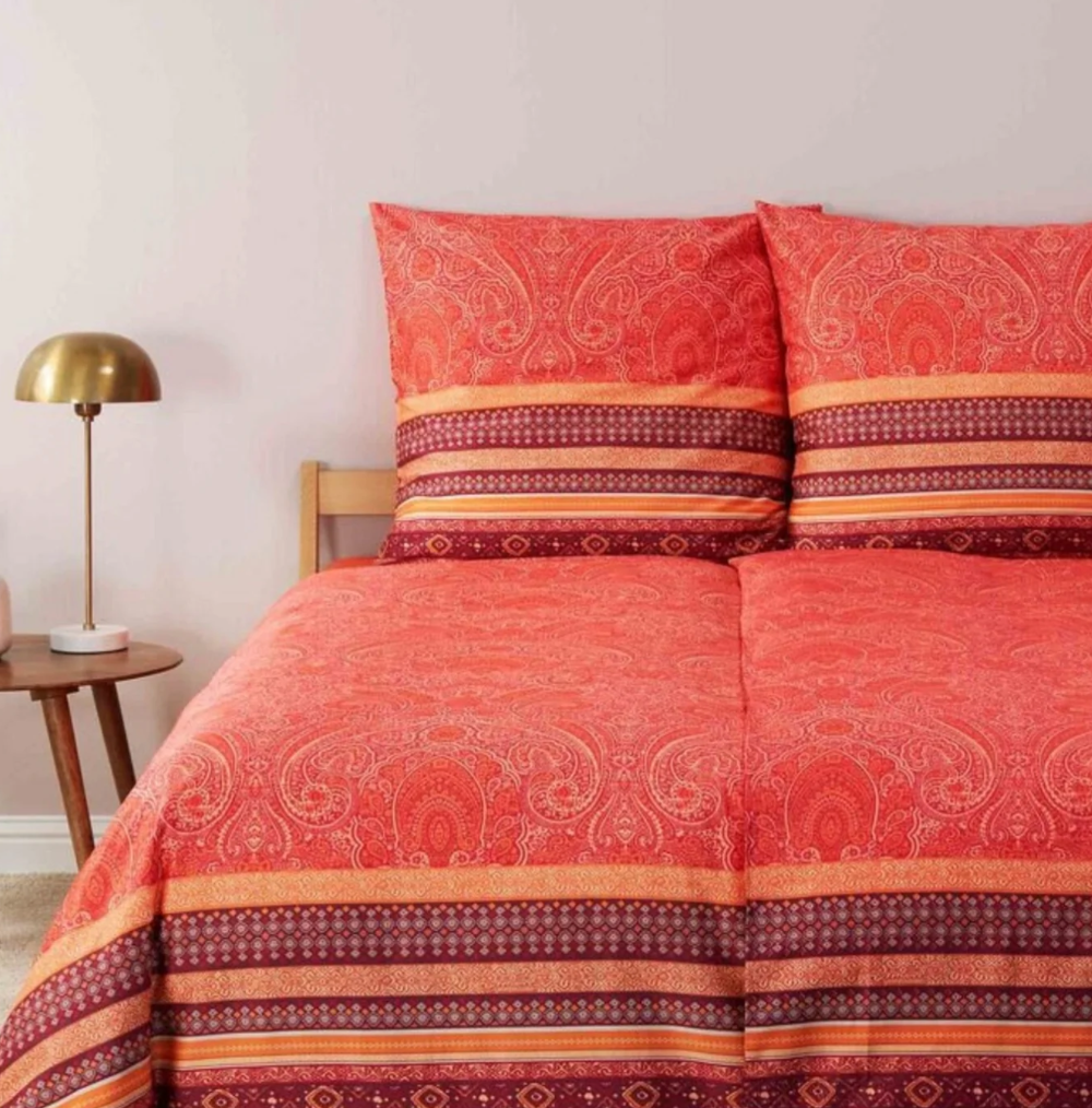 Mehrere Kopfkissen und eine Bettdecke bezogen mit eleganter Mako-Satin Bettwaesche von bassetti mit einem Paisleymuster in der Farbe Rot. Modell Maser R1