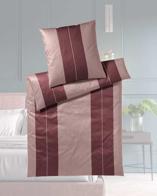 Ein Bettbezug-Set aus einem Kopfkissen und einer Bettdecke bezogen mit seidig-weicher Mako-Satin Bettwaesche aus 100 Prozent Baumwolle mit vertikalen Streifen in der Farbe Bordeaux. Modell Burgundy.