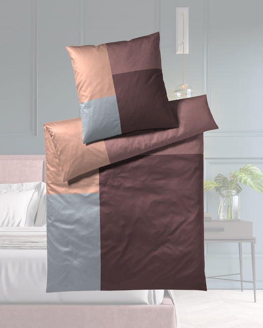 Ein Bettbezug-Set aus einem Kopfkissen und einer Bettdecke bezogen mit seidig-weicher Mako-Satin Bettwaesche aus 100 Prozent Baumwolle mit Karomuster in der Farbe Bordeaux. Modell Karo Bordeaux.