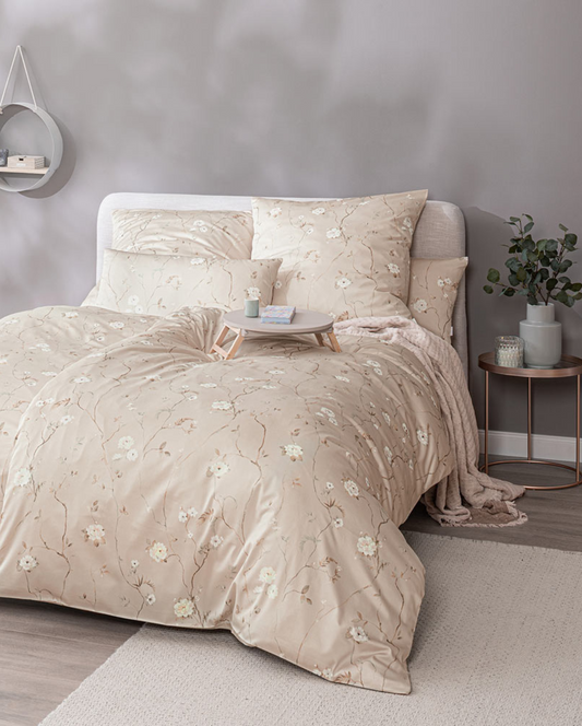 Ein Bettbezug-Set aus mehreren Kopfkissen und einer Bettdecke bezogen mit Mako-Satin Bettwaesche aus 100 Prozent Baumwolle mit Muster aus Blumen in der Farbe Beige. Modell Soralya Puder.