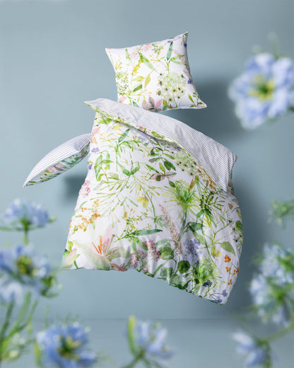 Ein Bettbezug-Set aus mehreren Kopfkissen und einer Bettdecke bezogen mit Mako-Satin Bettwaesche aus 100 Prozent Baumwolle mit Muster aus Blumen in der Farbe Weiss. Modell Summer.
