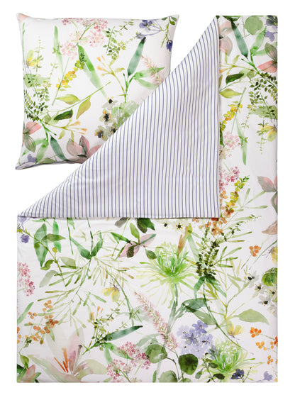 Ein Kopfkissen und eine Bettdecke bezogen mit Mako-Satin Bettwaesche mit einem Muster aus Blumen in der Farbe Weiss. Modell Summer.