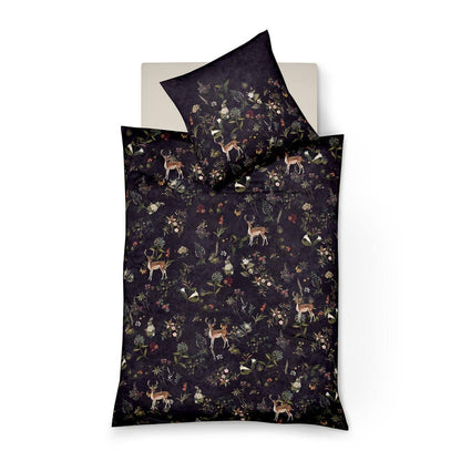 Ein Kopfkissen und eine Bettdecke bezogen mit Mako-Satin Bettwaesche mit einem Muster aus Waldtieren und Pflanzen in der Farbe Lila. Modell Forest.